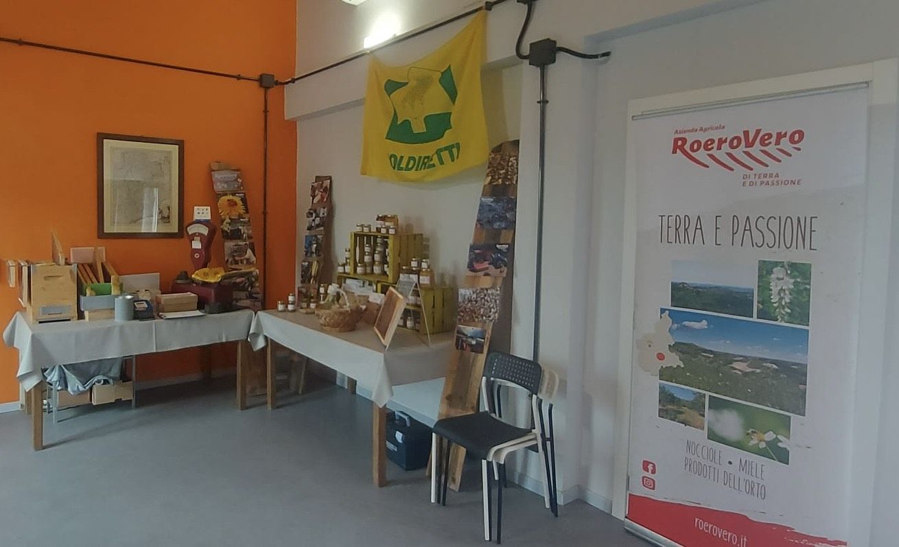 Interno del negozio, con due tavoli che espongono i prodotti, quali miele e nocciole.